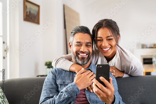 Happy indian couple using smartphone at home