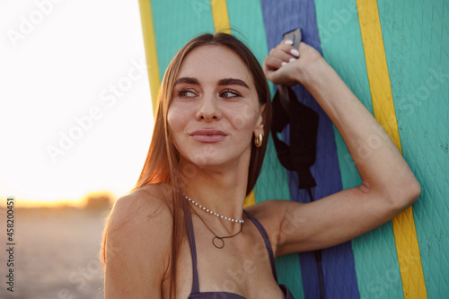 Attractive young woman in swimsuit posing with stand up paddle board photo