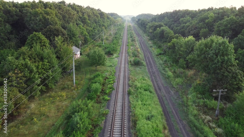 Fototapeta premium Railway tracks through forests and fields.