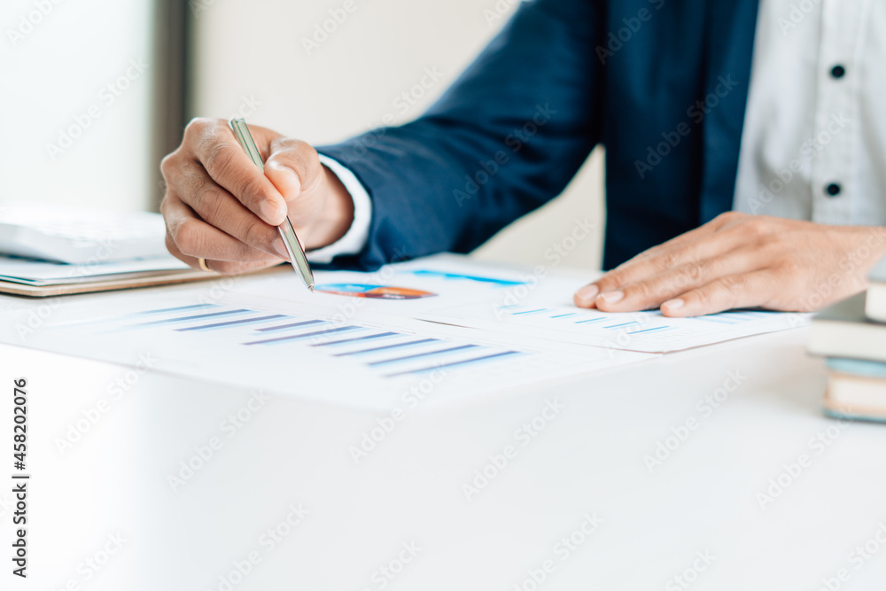 Businessman discussing analysis charts or graphs on desk table and using laptop computer.Close up male analysis and strategy concept. Businessman discussing analysis charts or graphs on desk table and using laptop computer.Close up male analysis and strategy concept.