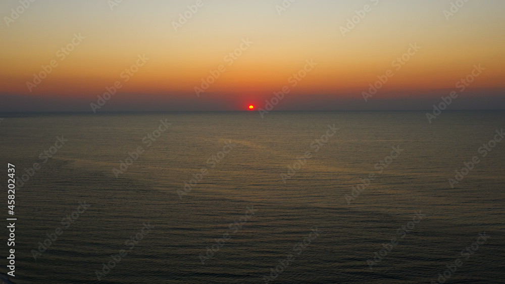 Panoramic view. Early sunrise over the Black Sea. Filmed by drone from bird's eye view. Full relax. Beautiful morning sunrise in light haze in autumn. Screensaver on computer, wallpaper for desktop.