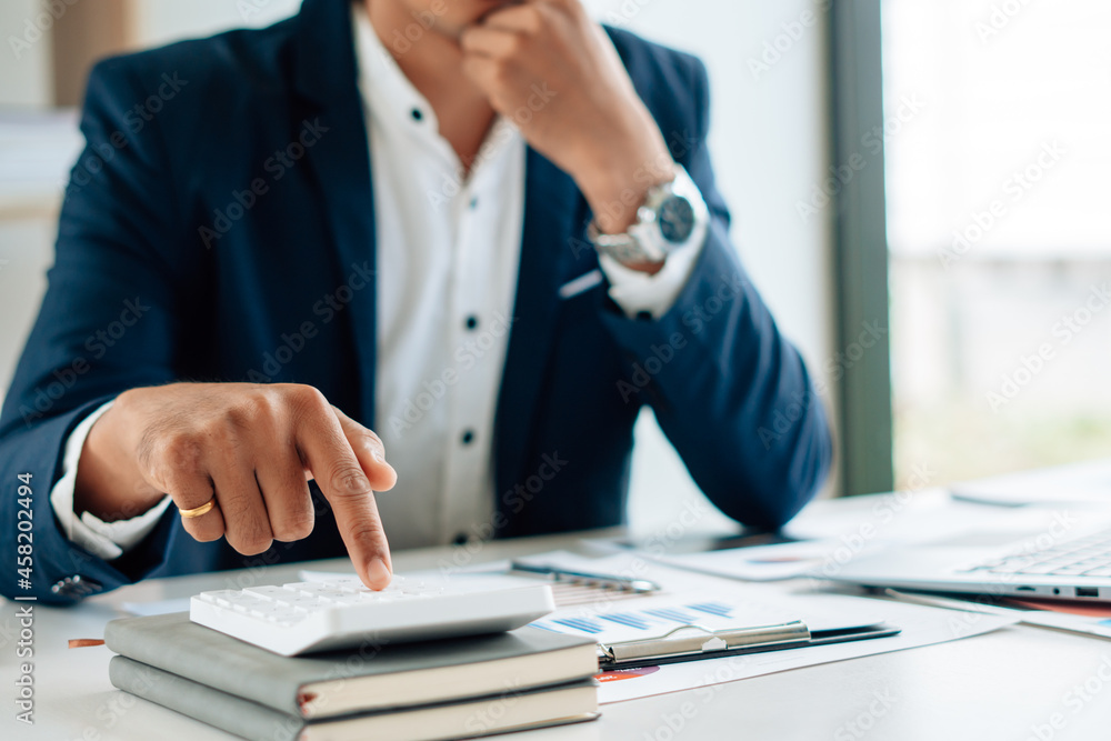 Businessman's hands with calculator at the office and Financial data analyzing counting on wood desk Businessman's hands with calculator at the office and Financial data analyzing counting on wood desk