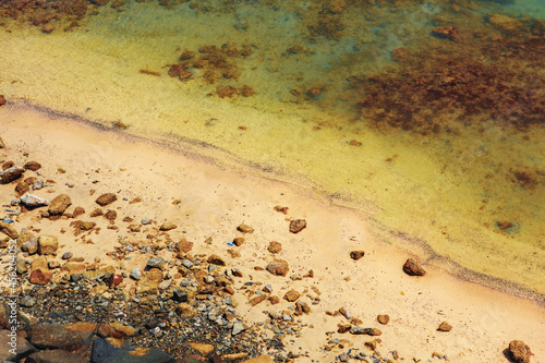 Fototapeta Naklejka Na Ścianę i Meble -  Close up of stones and clear water on the shore of a beach