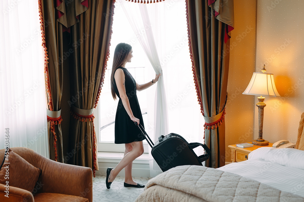 Fototapeta premium Young women with suitcase are staying in a hotel room.