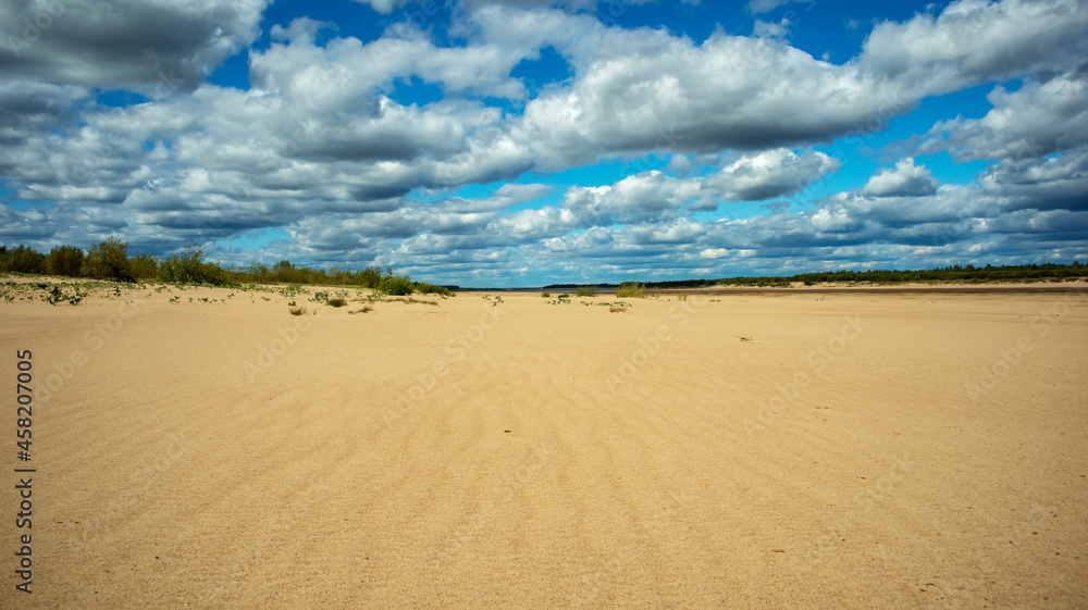 sandy coast against the backdrop of cumulus clouds on a sunny day,