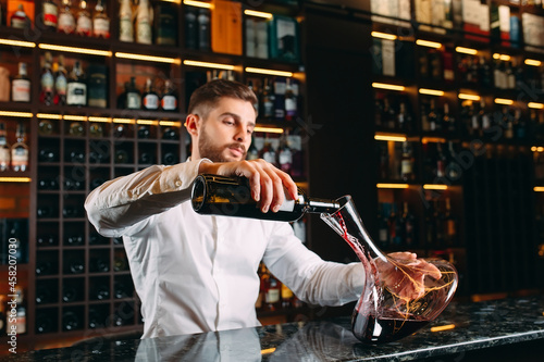 Young handsome man sommelier tasting red wine in cellar.