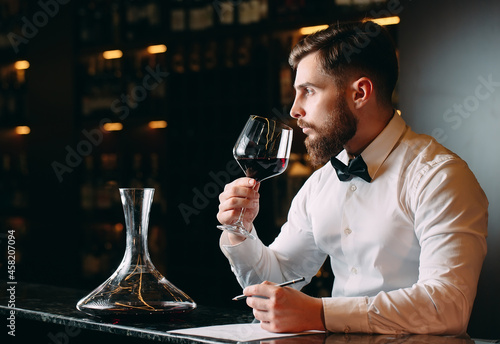 Young handsome man sommelier tasting red wine in cellar. photo
