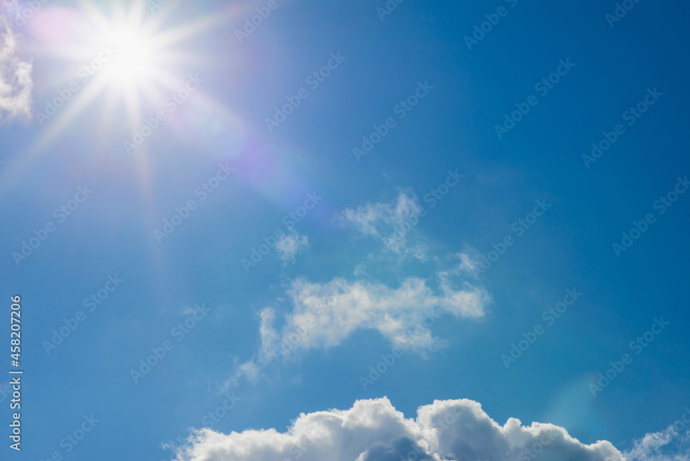 Shining sun at clear blue sky,clouds.Solar lens flare. copy space.Natural lens flare.Sunrays of bright sun on summer day.