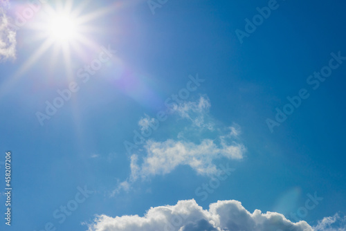Shining sun at clear blue sky clouds.Solar lens flare. copy space.Natural lens flare.Sunrays of bright sun on summer day.