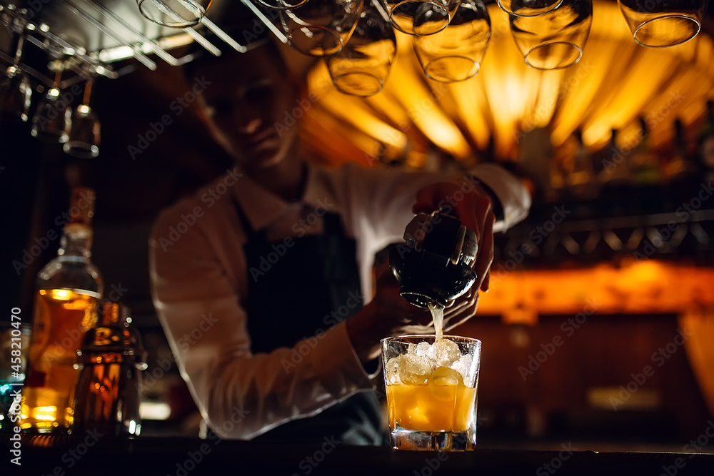 The bartender squeezes citrus juice into a cocktail.
