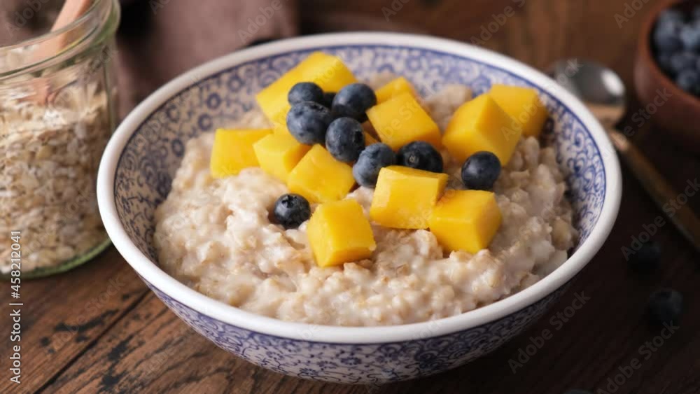 Cooked oatmeal with berries and fruits in bowl. Add blueberries in oatmeal porridge, healthy breakfast meal Cooked oatmeal with berries and fruits in bowl. Add blueberries in oatmeal porridge, healthy breakfast meal