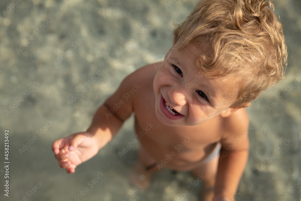 Authentic shot of happy smiling toddler baby boy is having fun to play in clear water of sea during family vacation holidays trip. Concept of travel, tourism, childhood, happiness and freedom. Authentic shot of happy smiling toddler baby boy is having fun to play in clear water of sea during family vacation holidays trip. Concept of travel, tourism, childhood, happiness and freedom.