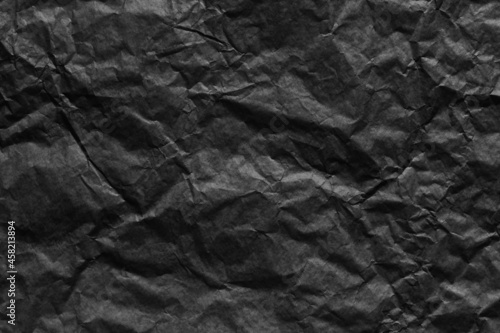 Black paper wrinkled texture background.