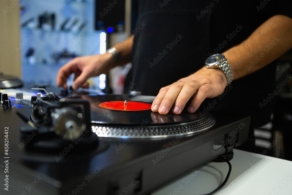 Dj scratching vinyl record on turntable. Disc jockey scratches records with turn tables and sound mixer in music store