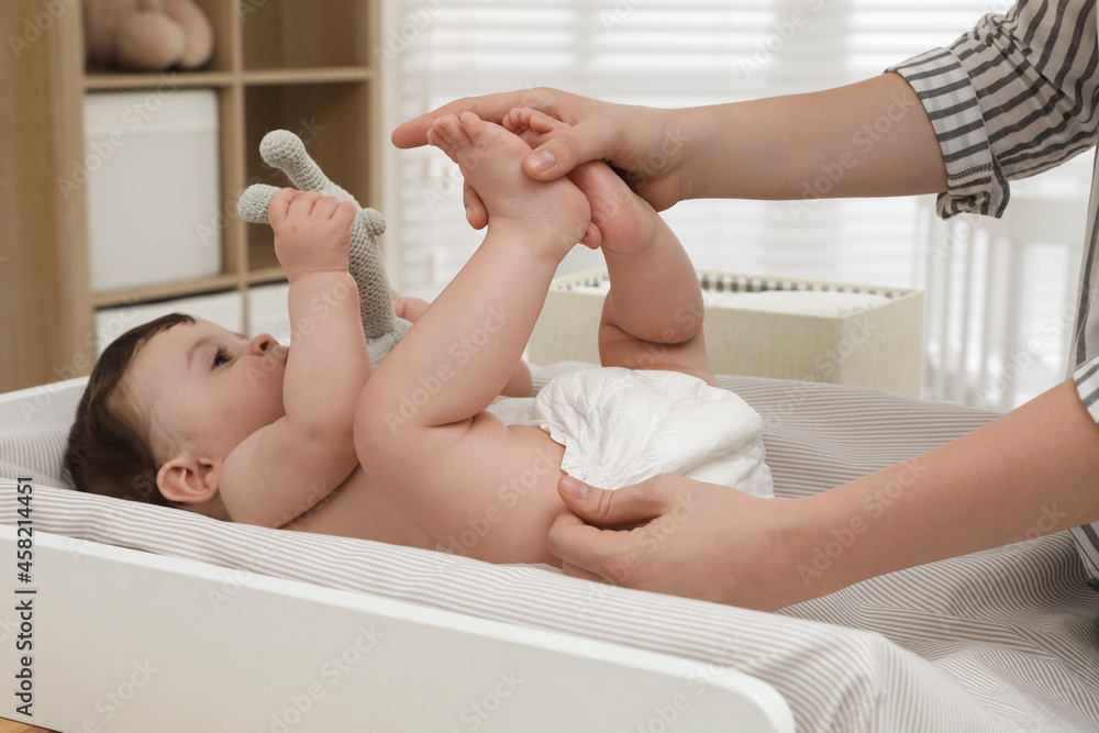 Mother changing baby's diaper on table at home, closeup Mother changing baby's diaper on table at home, closeup