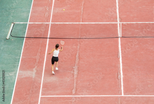 The girl plays tennis on court.