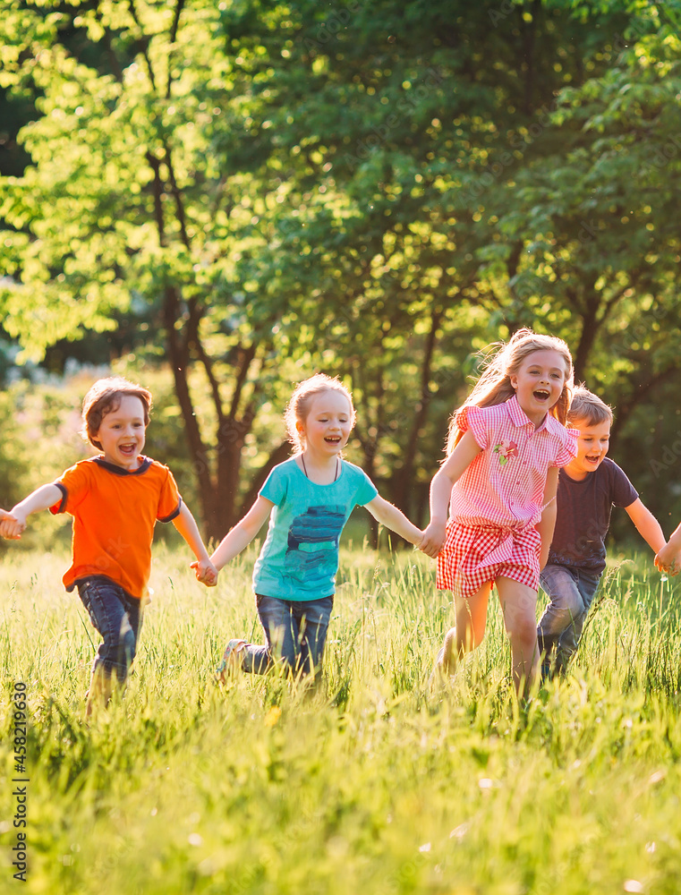 Large group of kids, friends boys and girls running in the park on sunny summer day in casual clothes .