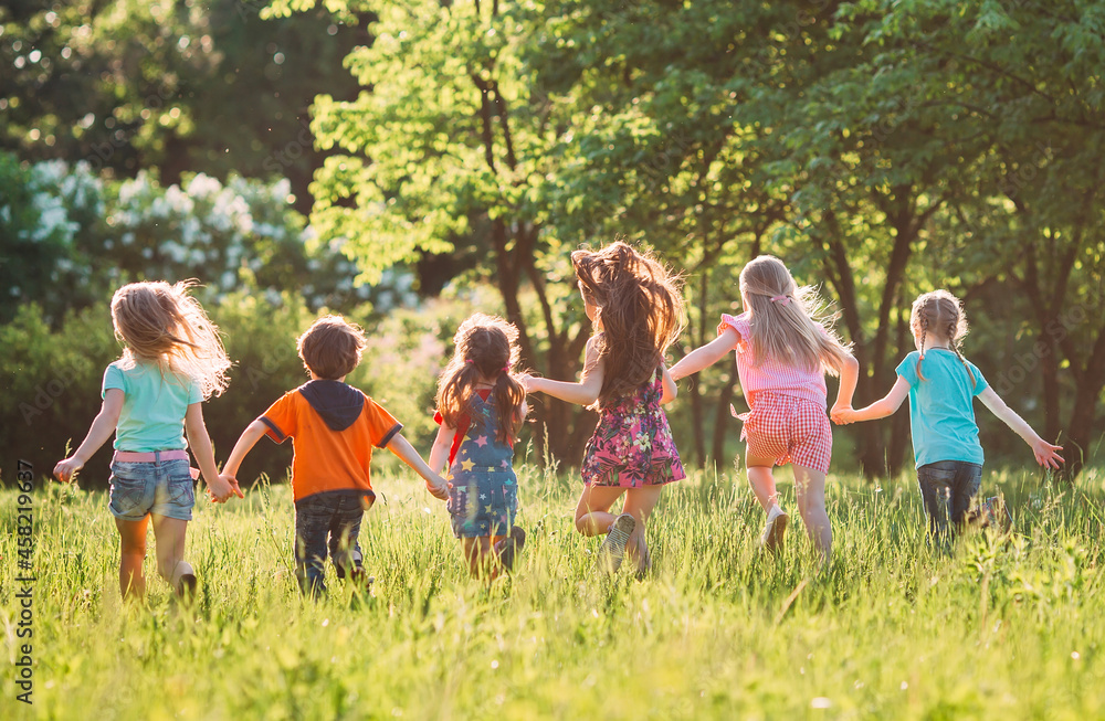 Obraz premium Large group of kids, friends boys and girls running in the park on sunny summer day in casual clothes .