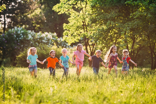 Large group of kids, friends boys and girls running in the park on sunny summer day in casual clothes . © davit85