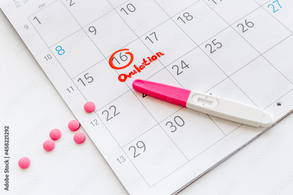 Ovulation home test and pills on calendarwith red mark Ovulation home test and pills on calendarwith red mark