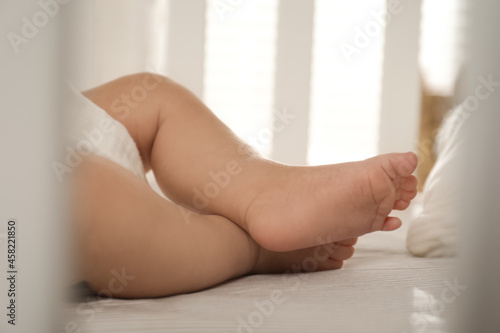 Cute little baby lying in soft crib, closeup