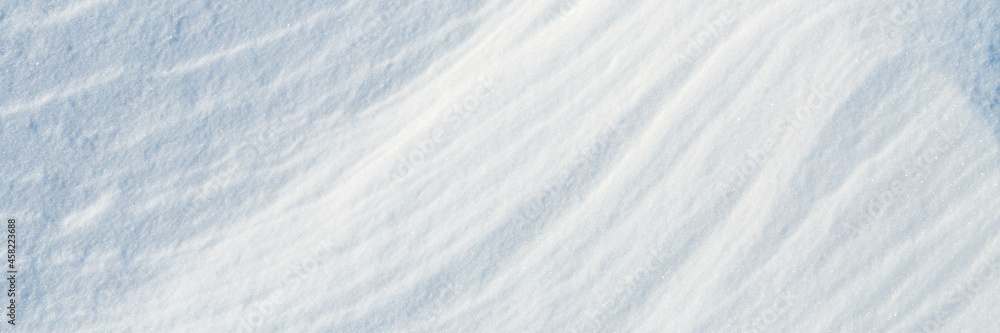 Beautiful winter background with snowy ground. Natural snow texture. Wind sculpted patterns on snow surface. Wide panoramic texture for background and design. Beautiful winter background with snowy ground. Natural snow texture. Wind sculpted patterns on snow surface. Wide panoramic texture for background and design.