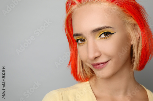 Beautiful young woman with bright dyed hair on light grey background, closeup. Space for text