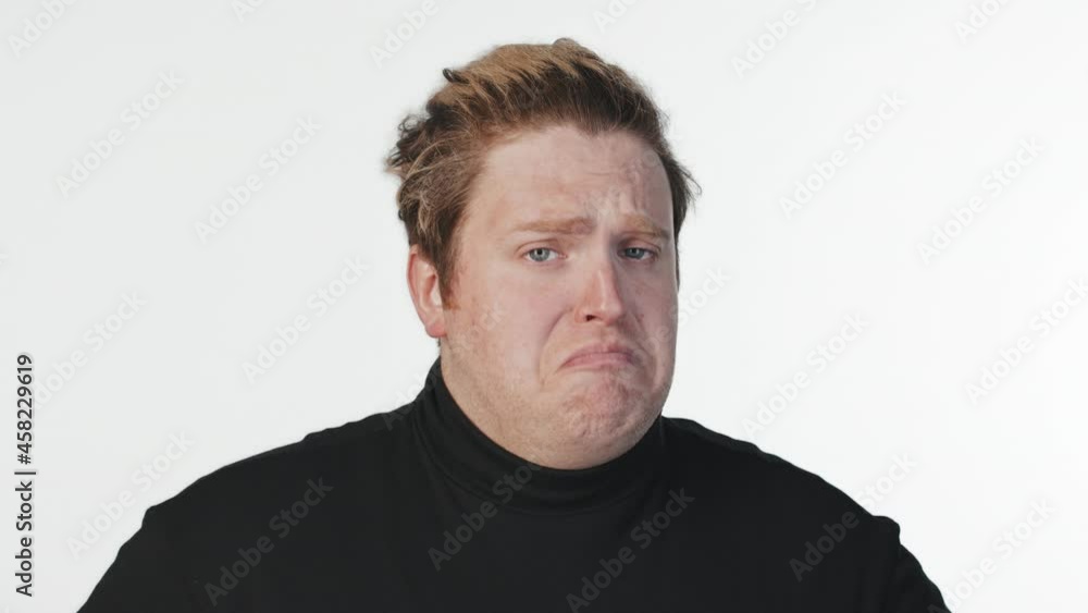 Medium close-up portrait with slowmo of young man making not bad face expression, looking at camera, standing at white background Medium close-up portrait with slowmo of young man making not bad face expression, looking at camera, standing at white background