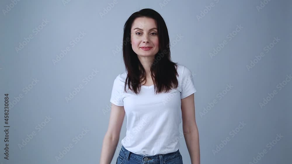 Beautiful young brunette woman dancing for video in studio. Pretty brunette model in 30s wearing casual white t-shirt and classic blue jeans Beautiful young brunette woman dancing for video in studio. Pretty brunette model in 30s wearing casual white t-shirt and classic blue jeans