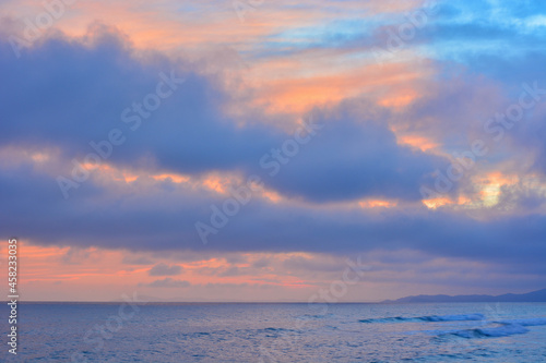 The sky above the sea during sunset or sunrise. Orange and blue colors.