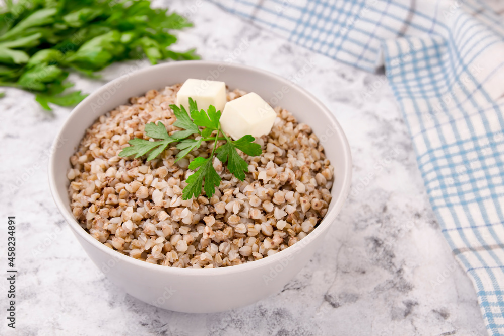 Boiled buckwheat in a plate with parsley leaf and butter on a white. Boiled buckwheat in a plate with parsley leaf and butter on a white.