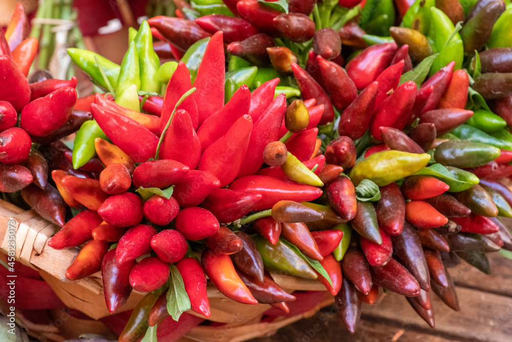 Bunches of red and green hot chili peppers in a basket in a street food market, close up Bunches of red and green hot chili peppers in a basket in a street food market, close up