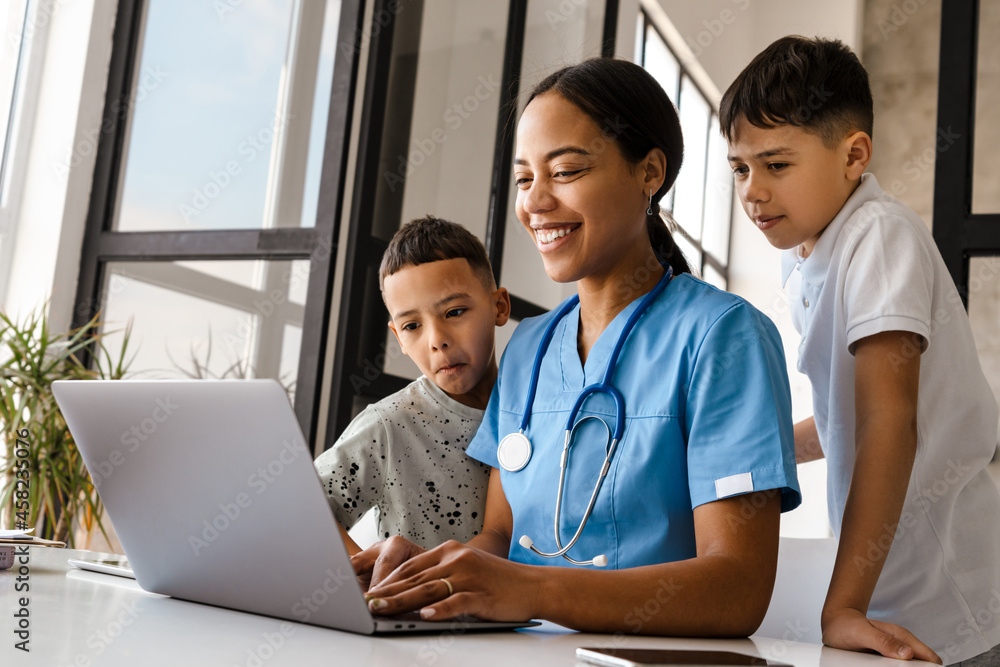 Black woman doctor working with laptop while sitting at table in home Black woman doctor working with laptop while sitting at table in home