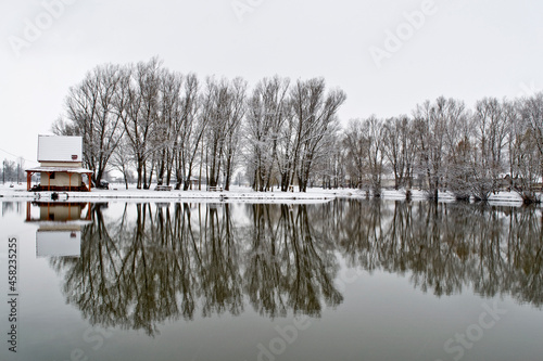 Small fishing house on the snowy lake side at winter. Ózd, Hungary. photo