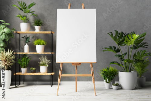 Photo Blank canvas on wooden easel with plant