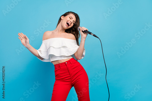 Portrait of attractive cheerful careless dreamy girl singing hit having fun rest isolated over vibrant blue color background photo