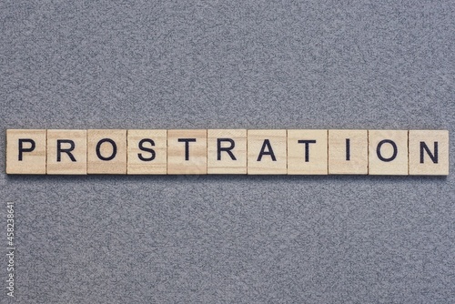 text the word prostration from gray wooden small letters with black font on an gray table