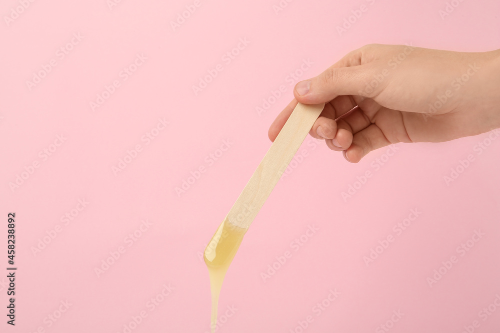 Woman holding spatula with hot depilatory wax on pink background, closeup. Space for text Woman holding spatula with hot depilatory wax on pink background, closeup. Space for text
