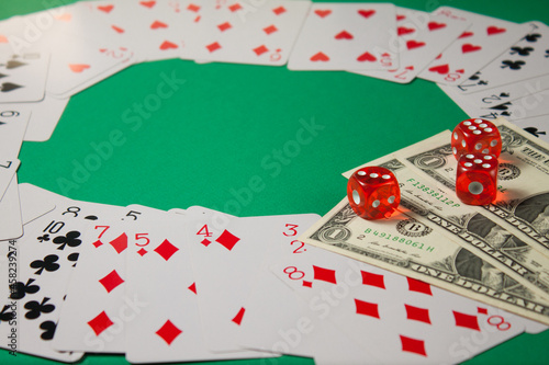 Classic playing cards, red dices and dollars on green background with place for text. Gambling and casino concept.