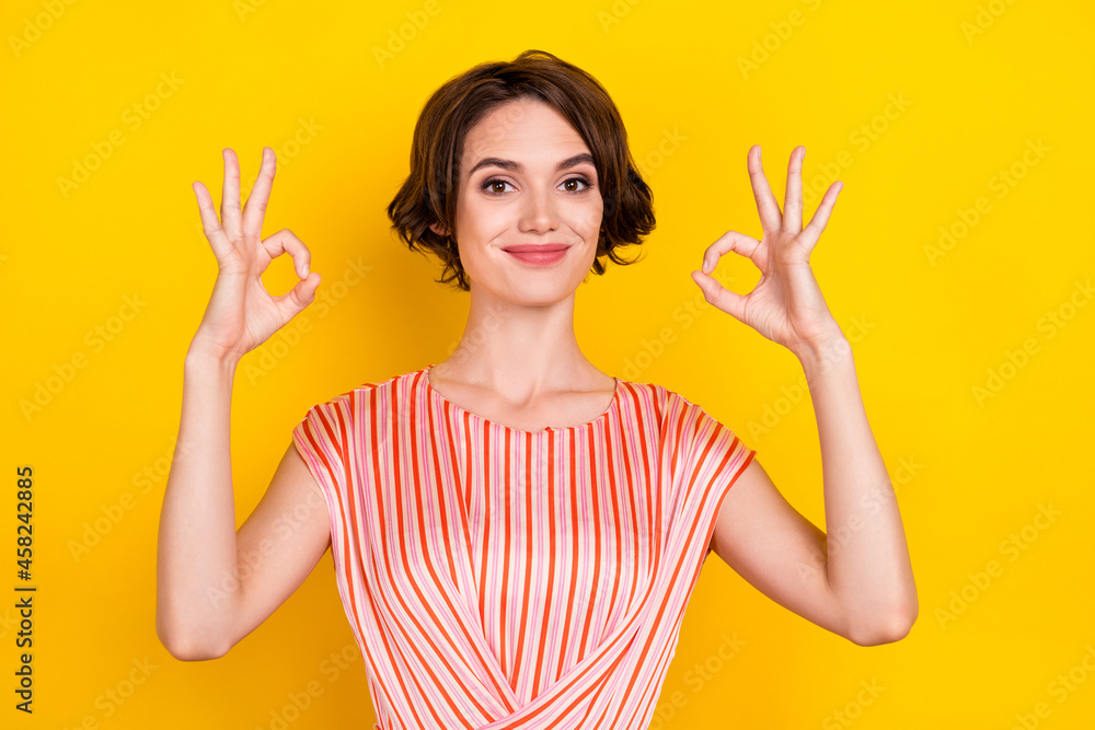 Portrait of attractive cheerful girl showing double ok-sign ad solution isolated over bright yellow color background Portrait of attractive cheerful girl showing double ok-sign ad solution isolated over bright yellow color background