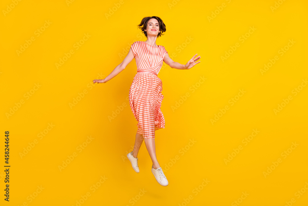 Photo of dream girl jump enjoy flight step wear striped dress sneakers isolated yellow color background Photo of dream girl jump enjoy flight step wear striped dress sneakers isolated yellow color background