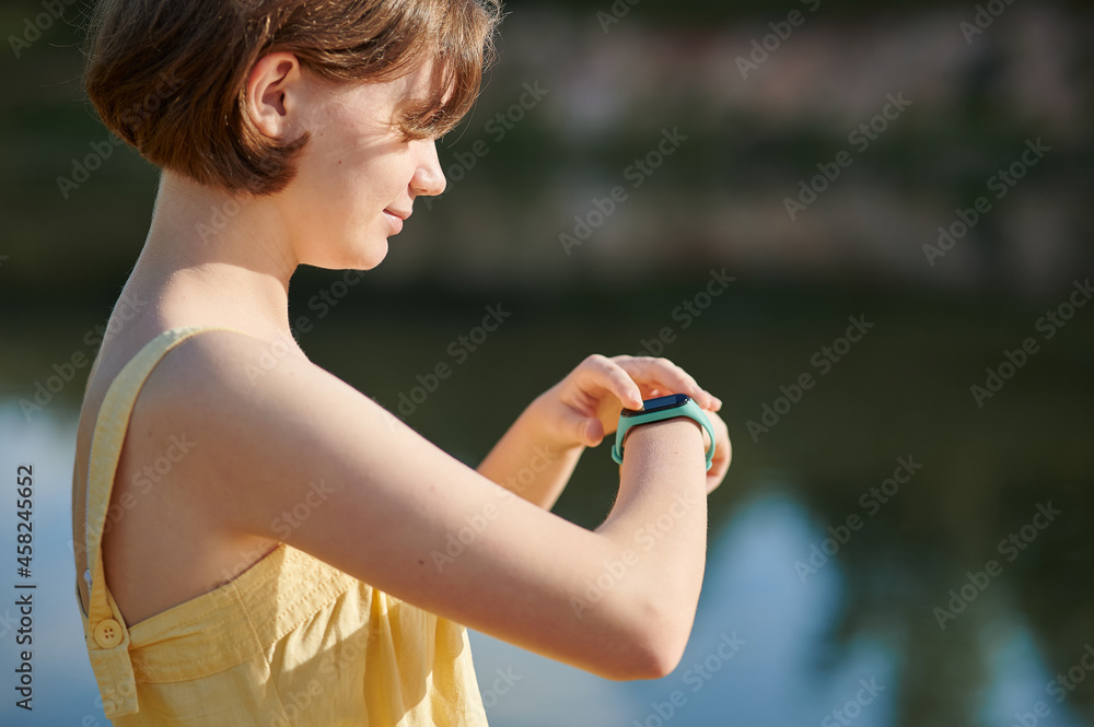 A teenage girl sets up a fitness tracker. Walking tour.