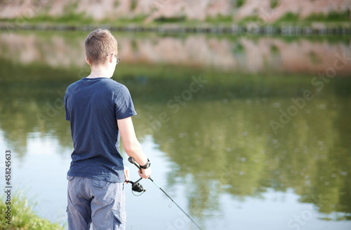 Young Man fishing on Lake with rod . Travel Lifestyle concept summer vacations.
