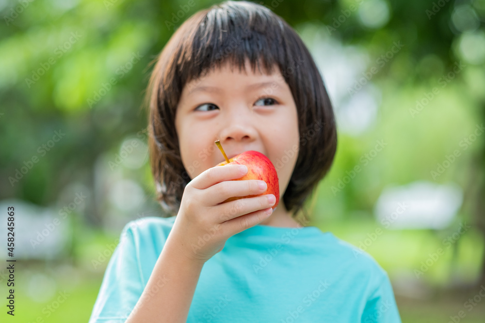 Children eating an apple with green nature background

