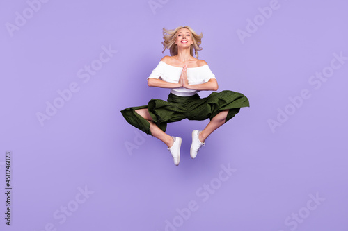 Full body photo of young woman happy positive smile jump up hands together ask wish isolated over purple color background