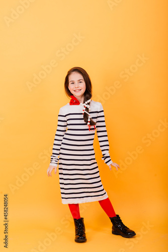 Close-up portrait of a cute little girl. Studio shot over yellow background. Childhood concept.