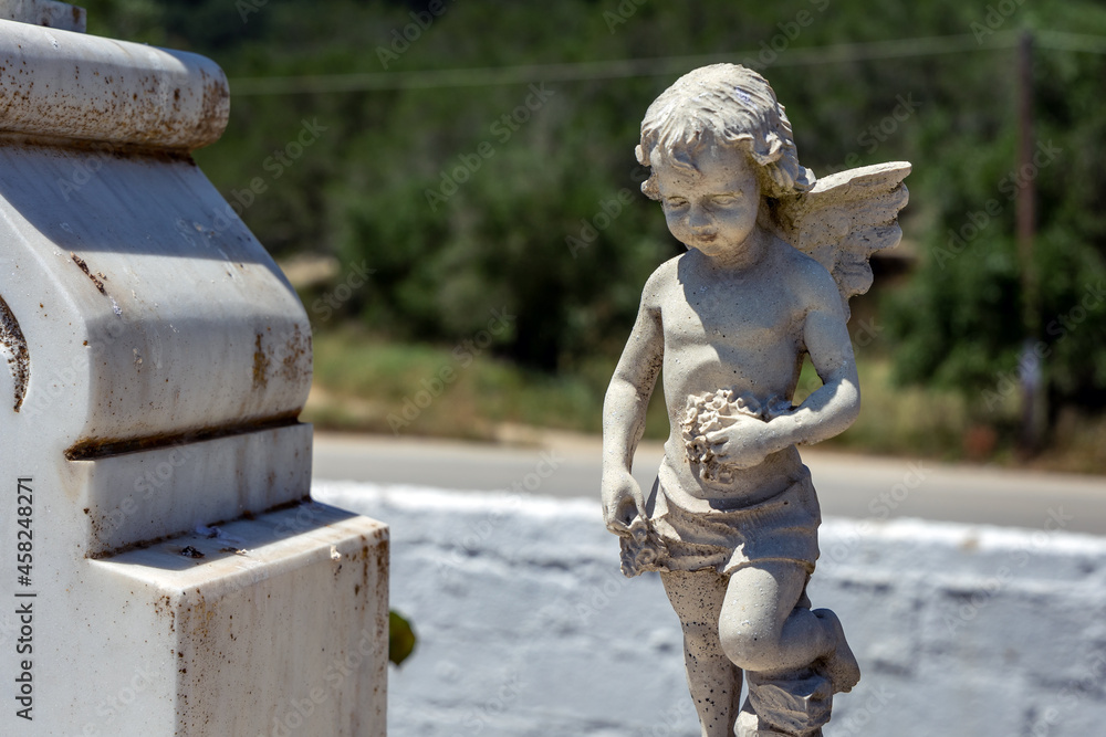 Angel statue on a grave on cemetery near Vouniatades, small town on Corfu Island, Greece Angel statue on a grave on cemetery near Vouniatades, small town on Corfu Island, Greece