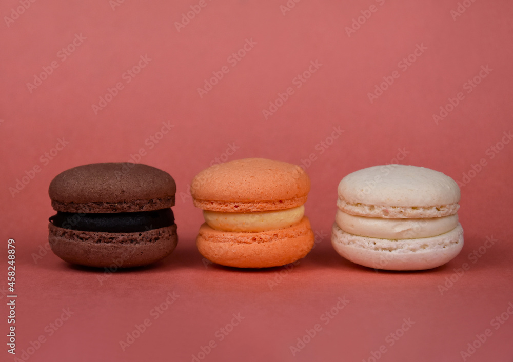 Orange, brown, white macarons in a row on a brown background stock images. Delicious french macarons isolated on a brown background with copy space for text Orange, brown, white macarons in a row on a brown background stock images. Delicious french macarons isolated on a brown background with copy space for text