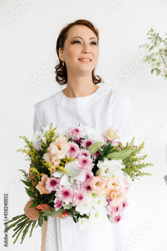 beautiful Caucasian I am a brunette girl in a white coat with a large bouquet of fresh flowers in her hands.