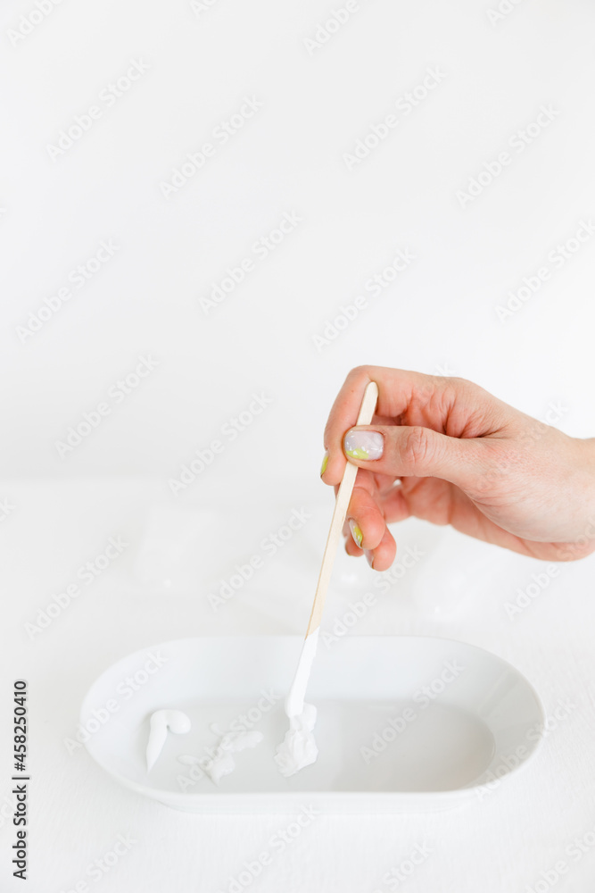a wooden stick is placed in an oval saucer with a cosmetic cream. there are several cream textures in a white saucer on a white background. Cosmetology and care. a wooden stick is placed in an oval saucer with a cosmetic cream. there are several cream textures in a white saucer on a white background. Cosmetology and care.